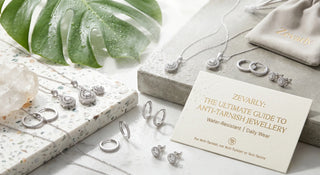 Premium flat lay of Zevarly water-resistant anti-tarnish jewellery featuring silver pendant sets and earrings with water droplets, a branded pouch, and a guide card.