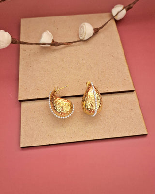 A pair of elegant gold earrings displayed on a rectangle, highlighting their intricate design and shine.