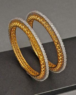 Pair of single line gokhru style  gold and silver bangles on a grey surface