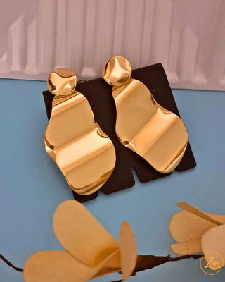 Gold plated earrings on a black stand with a blue background