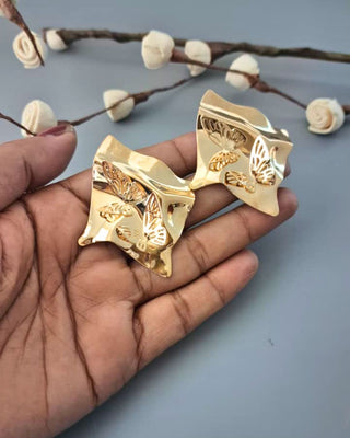 Gold decorative items on a hand with a light blue background