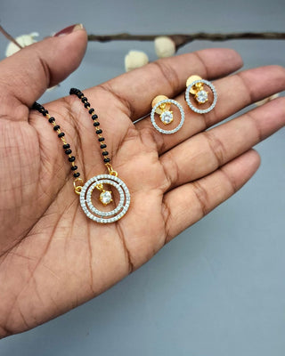 Jewelry set including a necklace and earrings on a hand against a neutral background