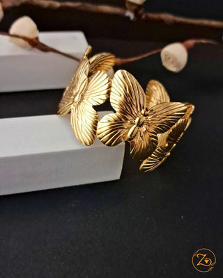 Gold butterfly-shaped cufflinks on a dark surface with a white block