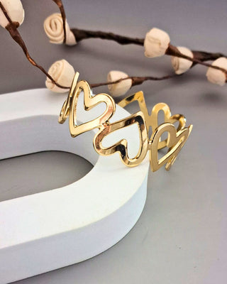 Gold heart-shaped hair clip on a white surface with decorative branches in the background