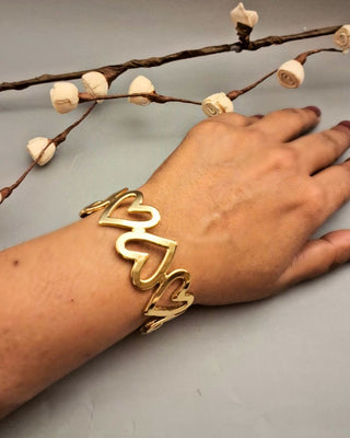 Gold bracelet on a wrist with a neutral background