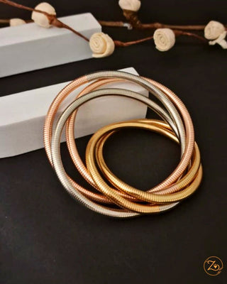 Set of gold and silver bangles on a dark surface with decorative elements.