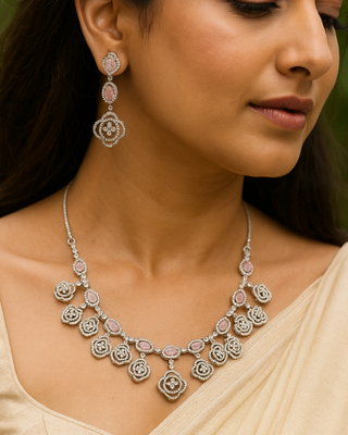 Woman wearing a silver necklace and earrings with pink gemstones.