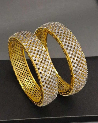 Gold and diamond-studded bangles on a black background