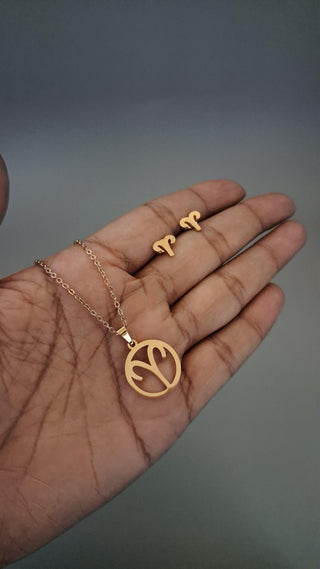 Gold necklace and ring on a hand against a gray background
