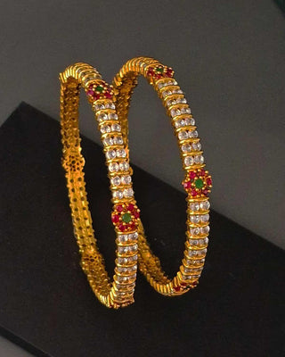 Gold bangles with gemstones on a black background