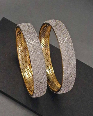 Two gold and silver bangles on a dark surface