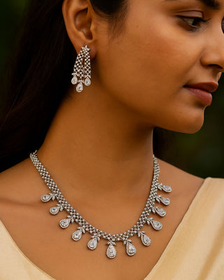 Woman wearing a silver necklace and earrings with a blurred background
