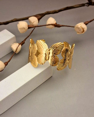 Gold bracelet on a gray surface with decorative branches and white blocks