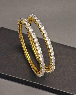Gold and silver bangles on a dark surface with a gray background