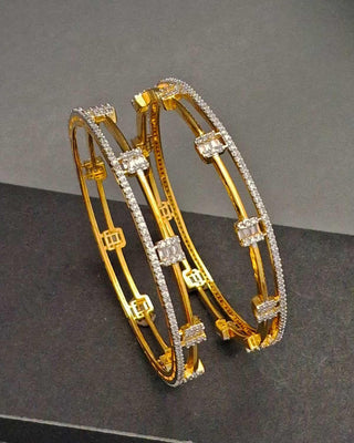 Gold bangles with diamond accents on a dark surface