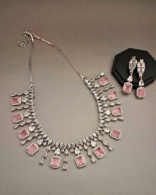 Jewelry set with necklace and earrings featuring pink stones on a gray background