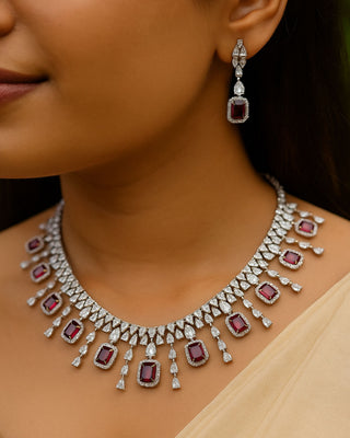 Close-up of a woman wearing a diamond and ruby necklace and earrings.