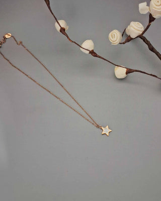 Gold star necklace on a gray background