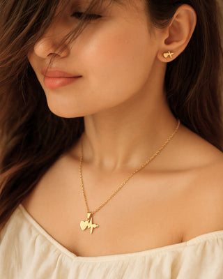 Close-up of a woman wearing a gold necklace and earrings.