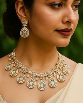 Woman wearing a gold and diamond necklace with matching earrings against a blurred green background