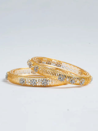 Gold bangles with diamond-like stones on a light gray background