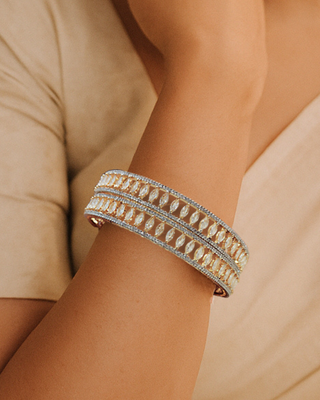 Close-up of a wrist wearing a gold bracelet with a neutral background