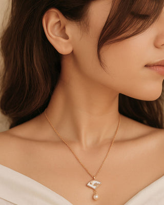Close-up of a woman wearing a delicate necklace with a heart-shaped pendant.