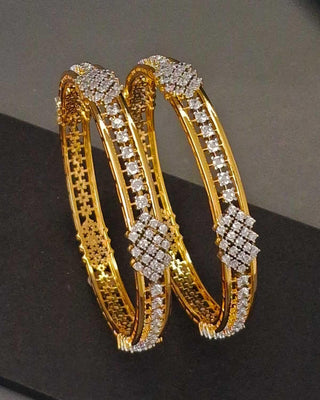 Zevarly Gold bangles with diamond embellishments on a black surface