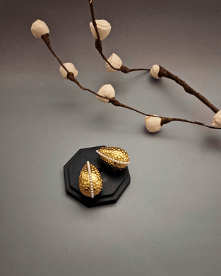 A pair of elegant gold earrings displayed on a sleek black stand, highlighting their intricate design and shine main image.