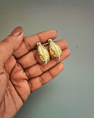 A pair of elegant gold earrings displayed on a hand, highlighting their intricate design and shine.