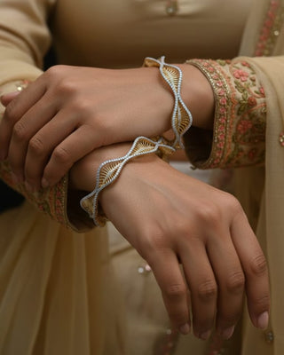 Close-up of hands wearing intricate bangles and a traditional outfit.